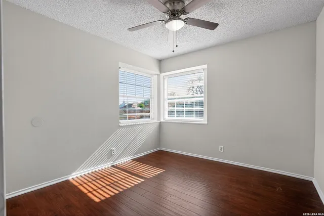 an empty room with wooden floor fan and windows