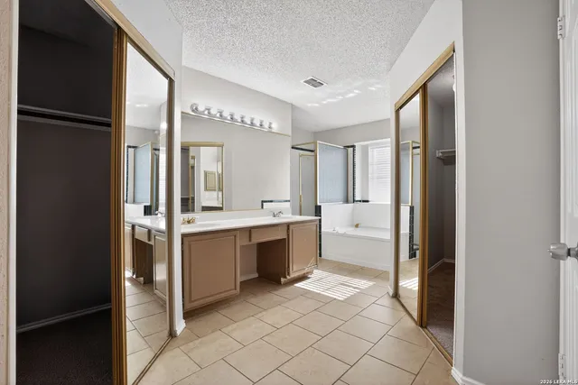 a bathroom with a double vanity sink mirror and a bathtub