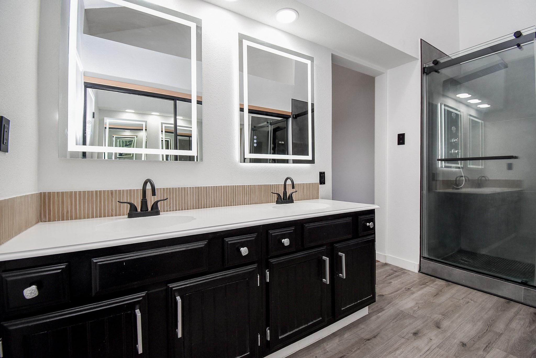 8715 Vinkins Road Houston, TX 77071 - Photo 31 of 48 Unwind in the beautifully updated primary bath featuring dual vanities, modern LED mirrors, stylish new fixtures and hardware, and an impressive walk-in frameless glass shower designed with today's lifestyle in mind.