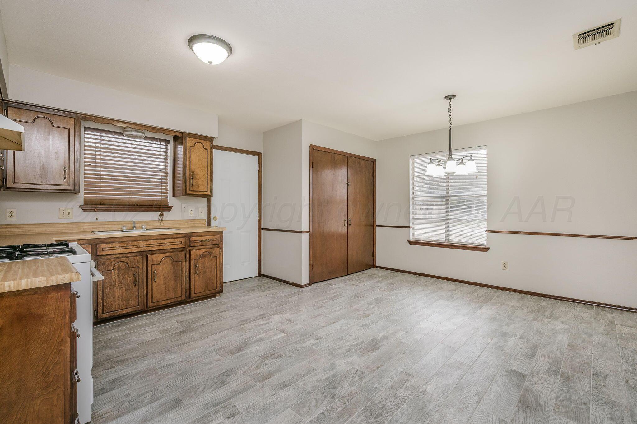 1624 Lockney Street Amarillo, TX 79106 - Photo 6 of 16 a kitchen with stainless steel appliances granite countertop a stove a sink dishwasher a refrigerator and white cabinets with wooden floor