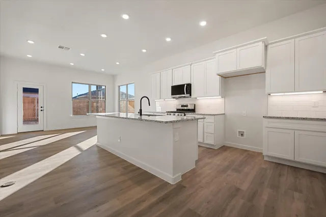 a kitchen with kitchen island granite countertop appliances cabinets and a sink