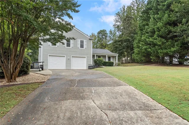 an aerial view of a house with a yard and trees all around