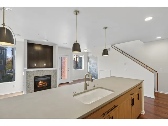 a kitchen with a sink a fireplace and a flat screen tv