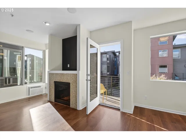 a view of an empty room with wooden floor and a fireplace