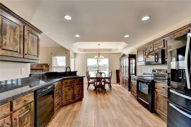 a kitchen with stainless steel appliances granite countertop a stove top oven a sink a dining table and chairs with wooden floor