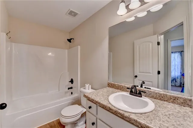a bathroom with a granite countertop sink toilet mirror and shower