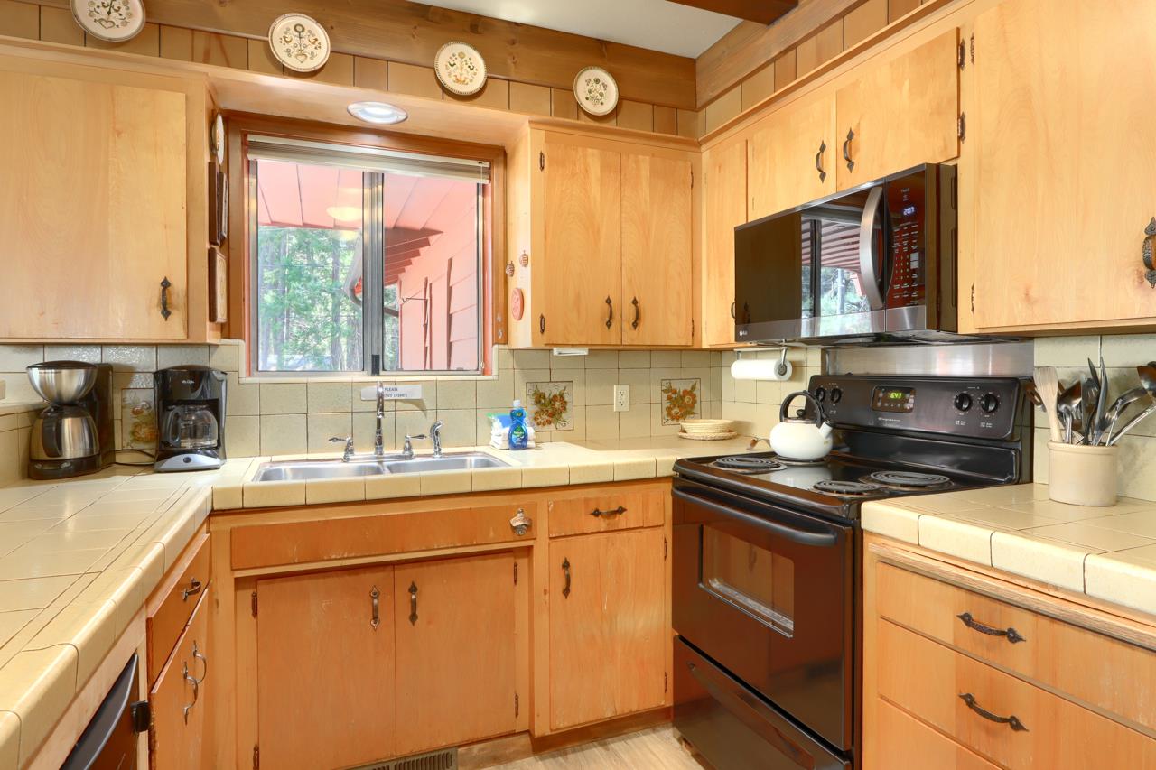 8067 Chilnualna Falls Road Wawona, CA 95389 - Photo 14 of 42 a kitchen with stainless steel appliances a sink stove and cabinets