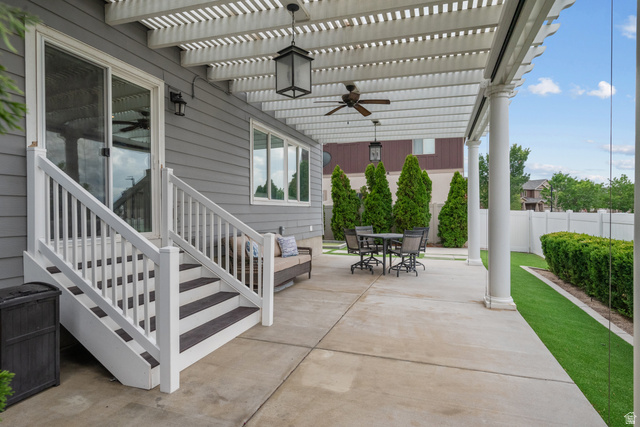 955 Delorean Lane Midvale, UT 84047 - Photo 41 of 47 Expansive concrete patio area featuring a white slatted pergola with ceiling fans and pendant lighting