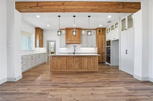 a large white kitchen with granite countertop a sink and white cabinets