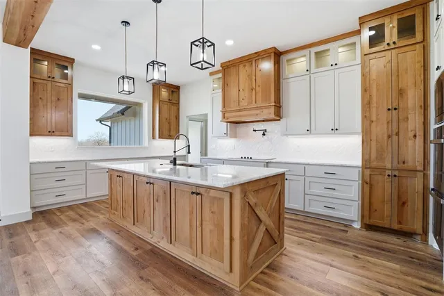 a kitchen with stainless steel appliances granite countertop a sink dishwasher a refrigerator and white cabinets with wooden floor