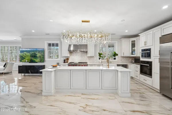 a kitchen with stainless steel appliances a sink a stove a refrigerator cabinets and a dining table