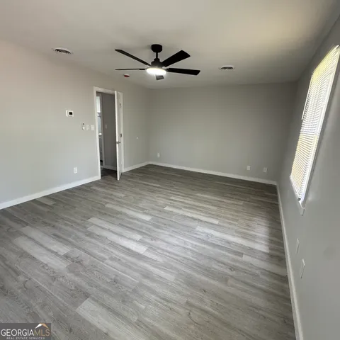 a view of an empty room with wooden floor and a window