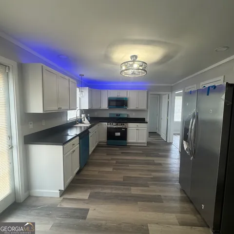 a large kitchen with stainless steel appliances kitchen island granite countertop a refrigerator and a stove top oven