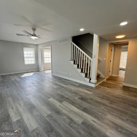 an empty room with wooden floor windows and a ceiling fan