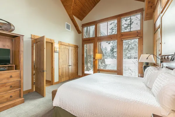 a bedroom with a large bed and a flat tv screen on dresser