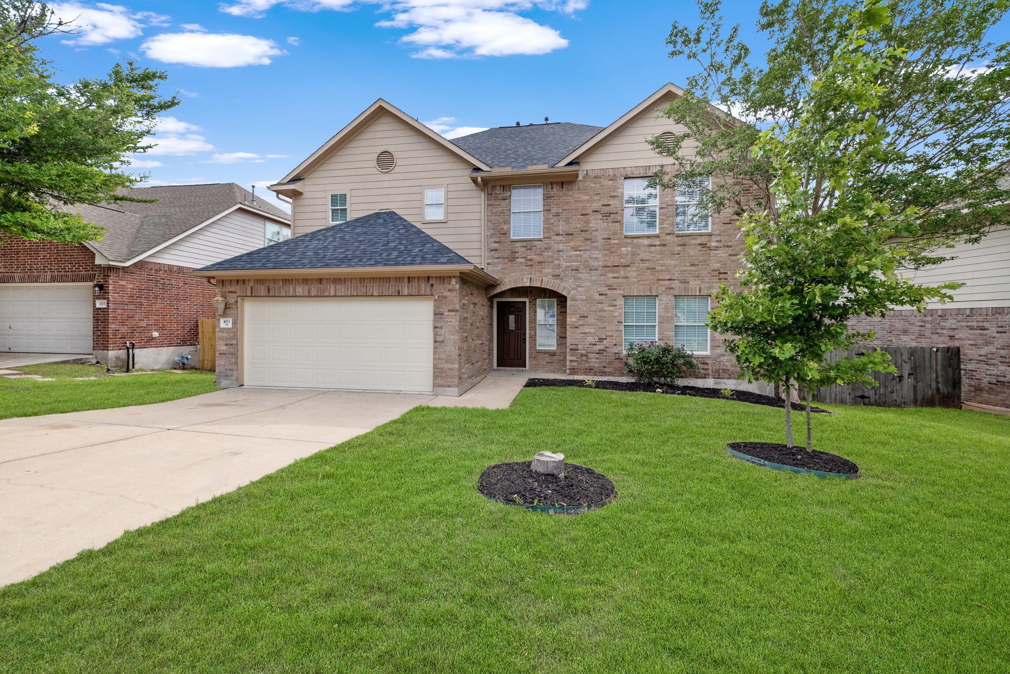 403 Red Hawk Drive Leander, TX 78641 - Photo 2 of 37 Two-story brick and siding residence featuring an attached two-car garage, established landscaping, a concrete driveway, and an arched entry