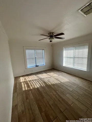 a view of an empty room with a window and wooden floor