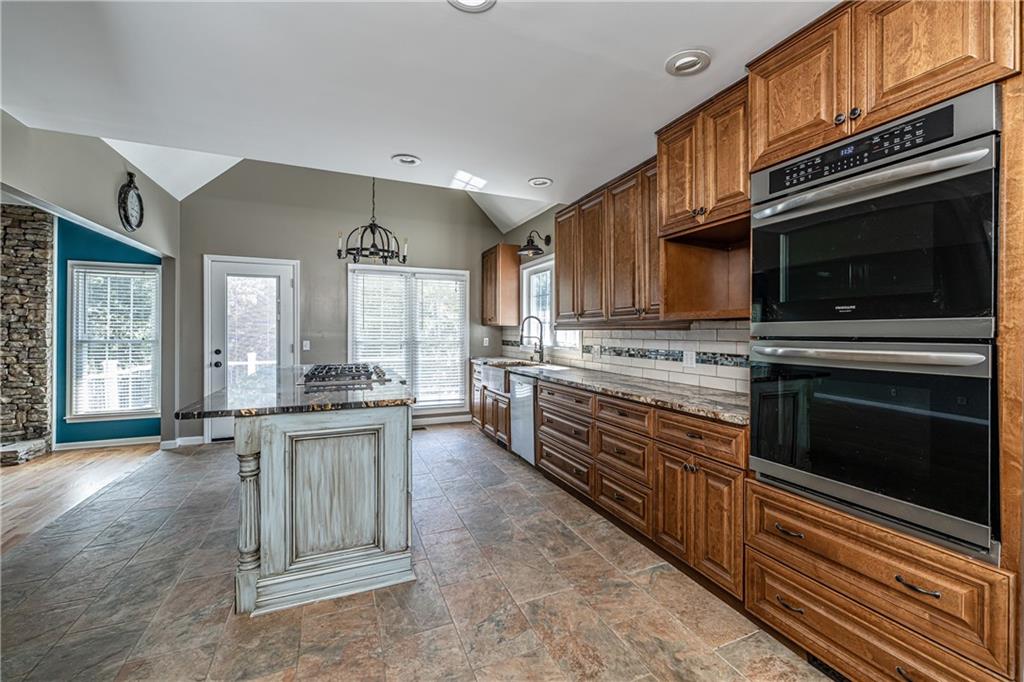 113 Warwick Way Rome, GA 30161 - Photo 14 of 49 a kitchen with stainless steel appliances kitchen island granite countertop a stove top oven a sink dishwasher a dining table and chairs with wooden floor
