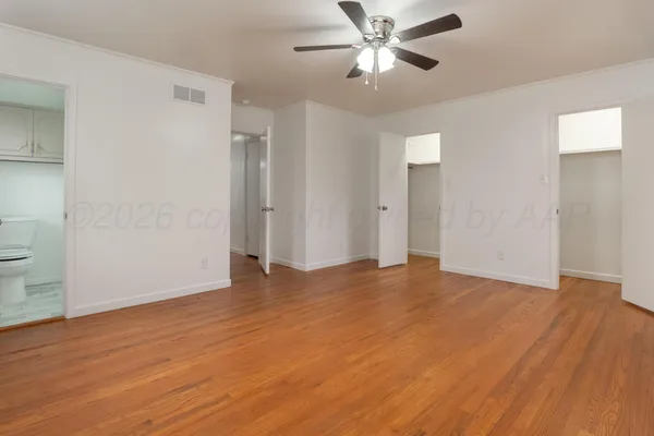 an empty room with wooden floor and ceiling fan