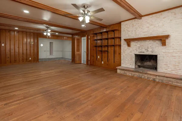 a view of an empty room with wooden floor fireplace and a window