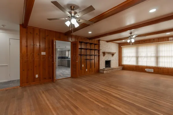 a view of an empty room with window and wooden floor