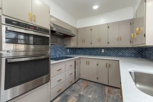 a kitchen with granite countertop white cabinets and stainless steel appliances