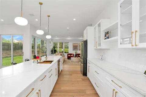 a large kitchen with kitchen island a large counter space a sink a stove and a chandelier