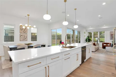 a kitchen with center island a sink dishwasher a dining table chairs and a large window