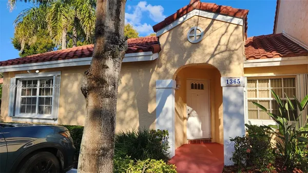 a view of a brick house with a large windows and flower plants