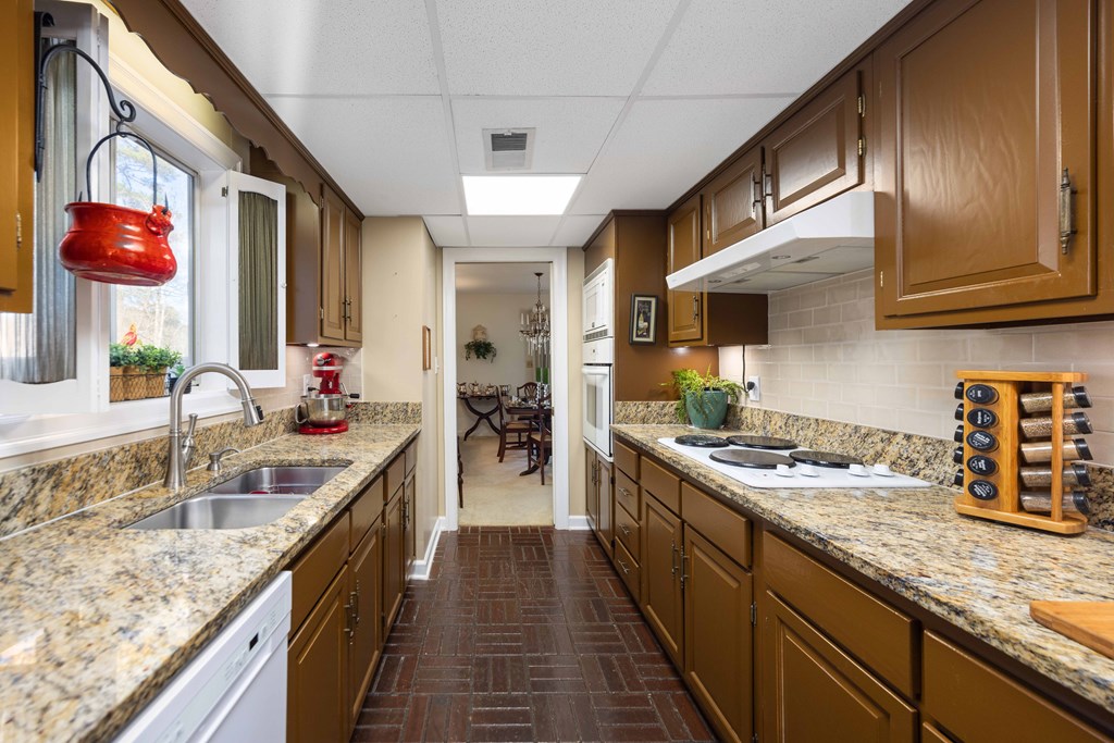 13965 Cross Creek Road Upatoi, GA 31829 - Photo 20 of 44 a kitchen with stainless steel appliances granite countertop a sink a stove and a wooden cabinets
