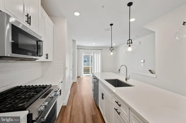 a kitchen with stainless steel appliances a sink a stove a microwave and wooden floor