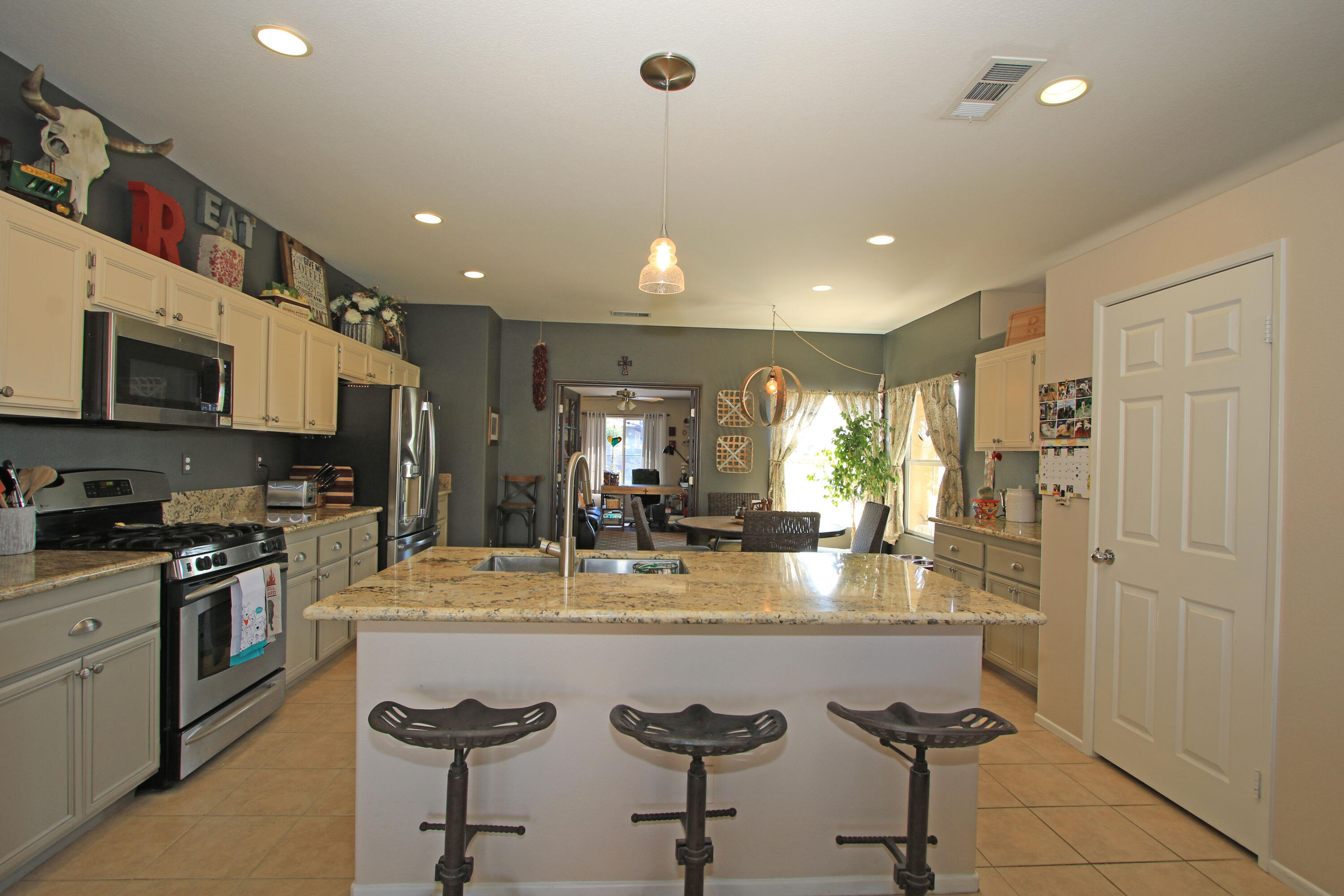 40651 Morris Street Indio, CA 92203 - Photo 15 of 47 a kitchen with stainless steel appliances granite countertop a refrigerator a stove a sink a dining table and chairs with wooden floor