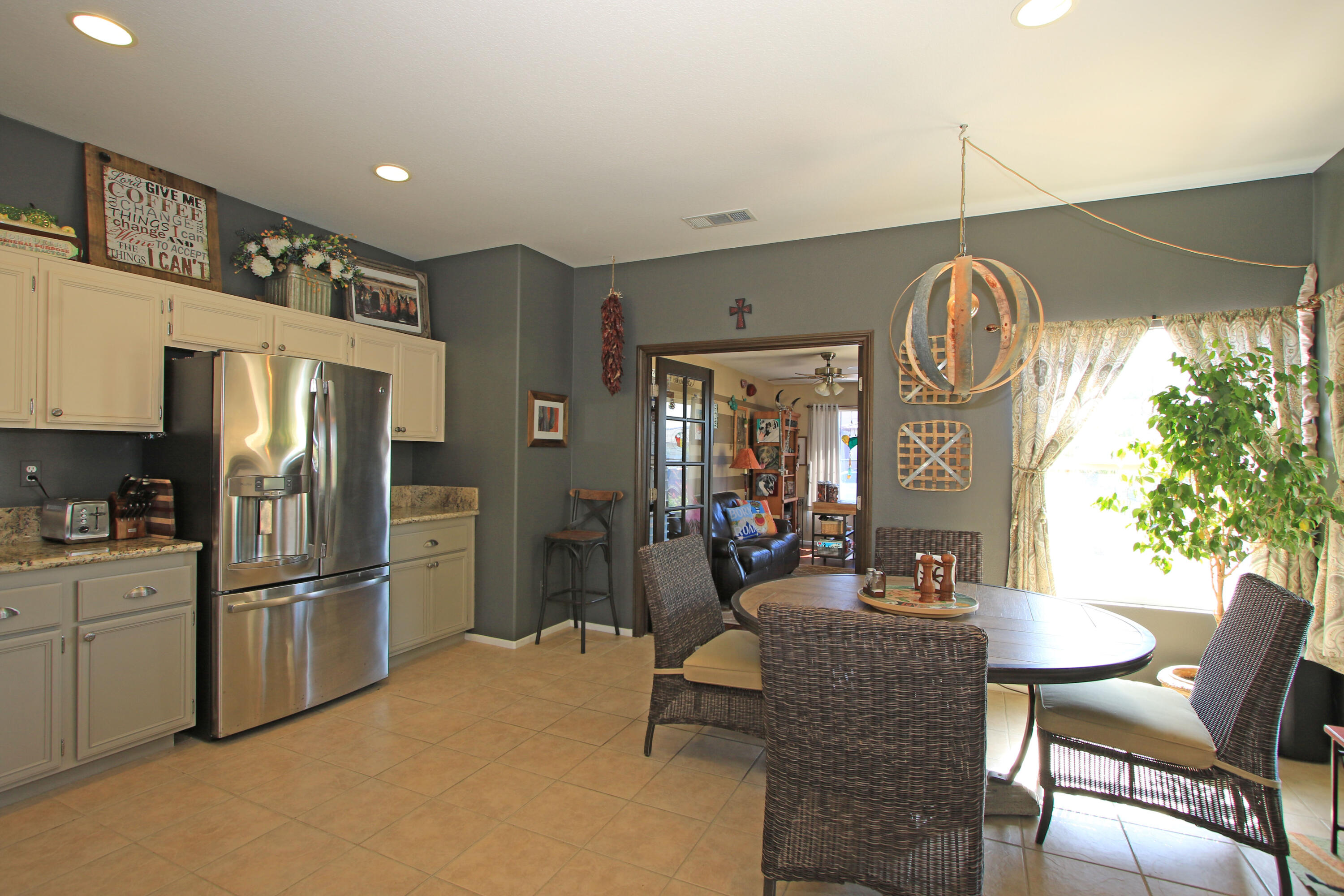 40651 Morris Street Indio, CA 92203 - Photo 10 of 47 a kitchen with stainless steel appliances granite countertop a refrigerator a stove a dining table and chairs with wooden floor