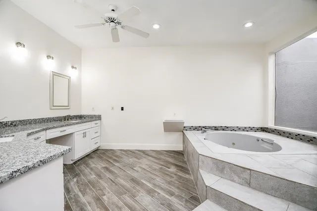 a spacious bathroom with a granite countertop sink and a bathtub