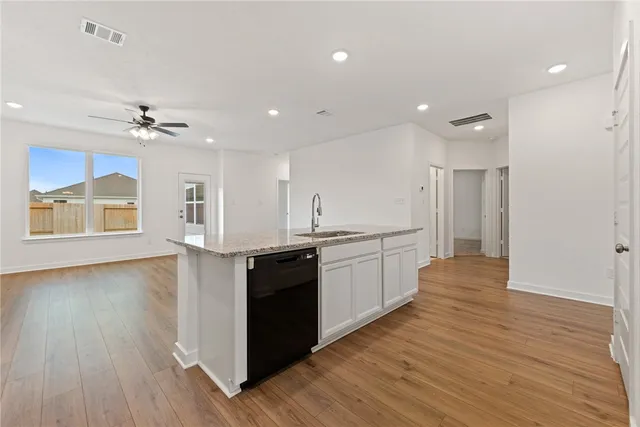a large kitchen with stainless steel appliances granite countertop a stove and a wooden floors