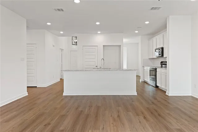 a view of kitchen with kitchen island wooden floor appliances and cabinets