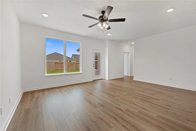 a view of an empty room with window and wooden floor