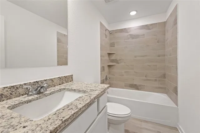 a bathroom with a granite countertop sink a toilet and bathtub