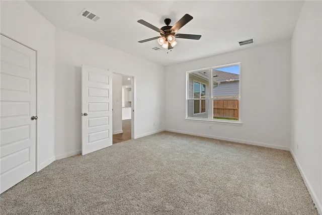 an empty room with closet and ceiling fan