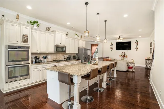 a large kitchen with granite countertop a sink a counter top space appliances and cabinets