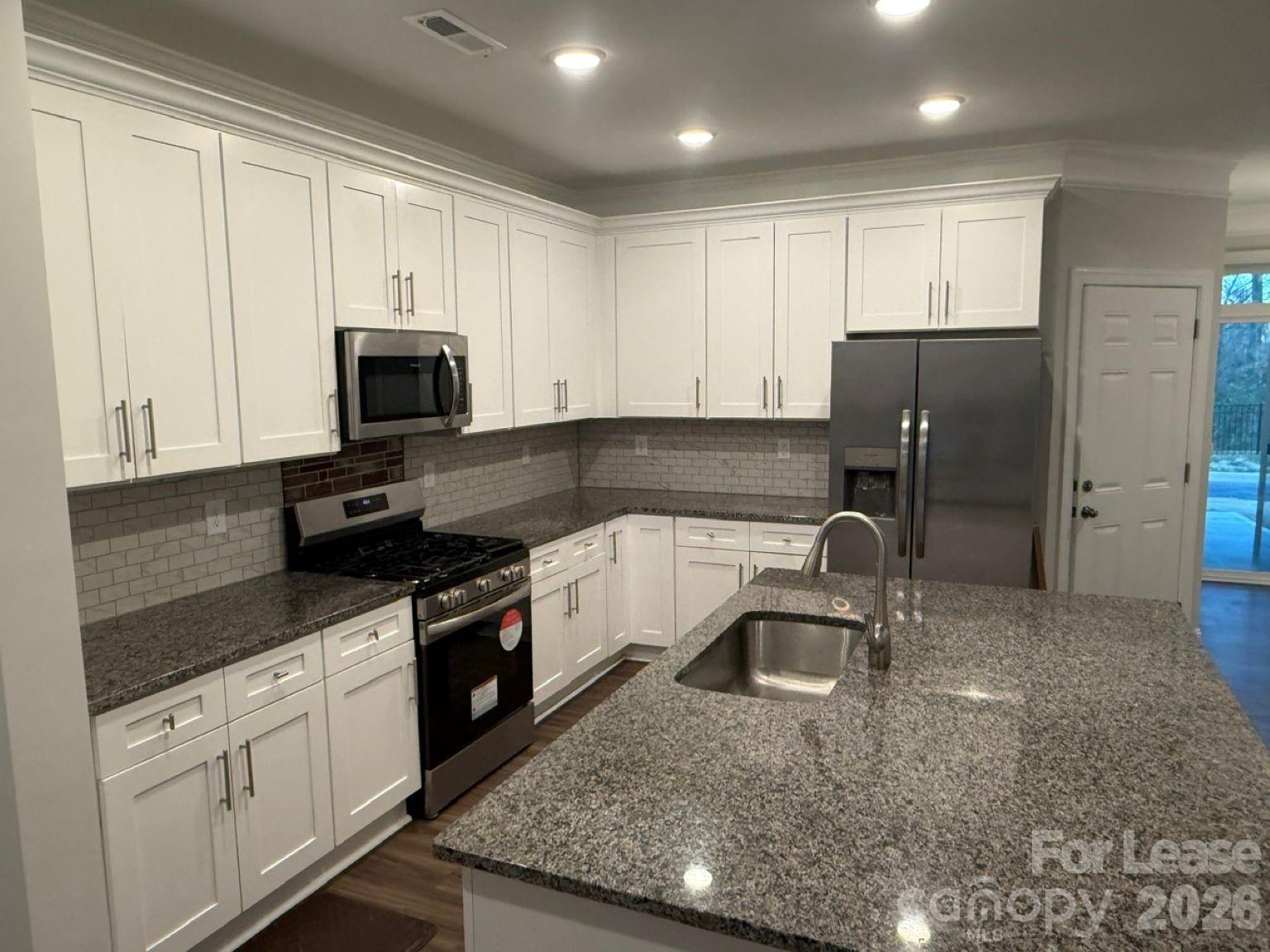 5593 Stafford Road Charlotte, NC 28215 - Photo 3 of 23 a kitchen with stainless steel appliances granite countertop a sink a stove a refrigerator a window and white cabinets