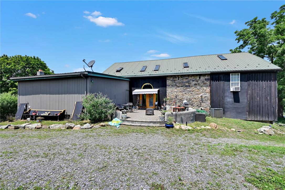 101 Conrad Road Fleetwood, PA 19522 - Photo 29 of 42 An inviting stone and wood-sided structure with a verdant metal roof offers a generous patio space, perfect for outdoor enjoyment.