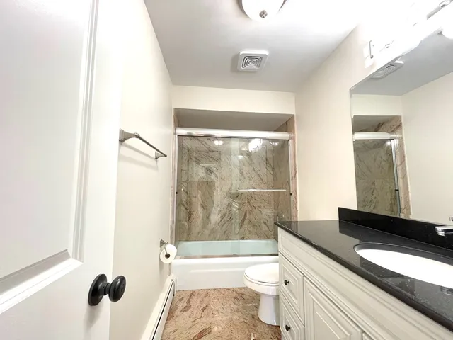a bathroom with a granite countertop sink toilet and shower