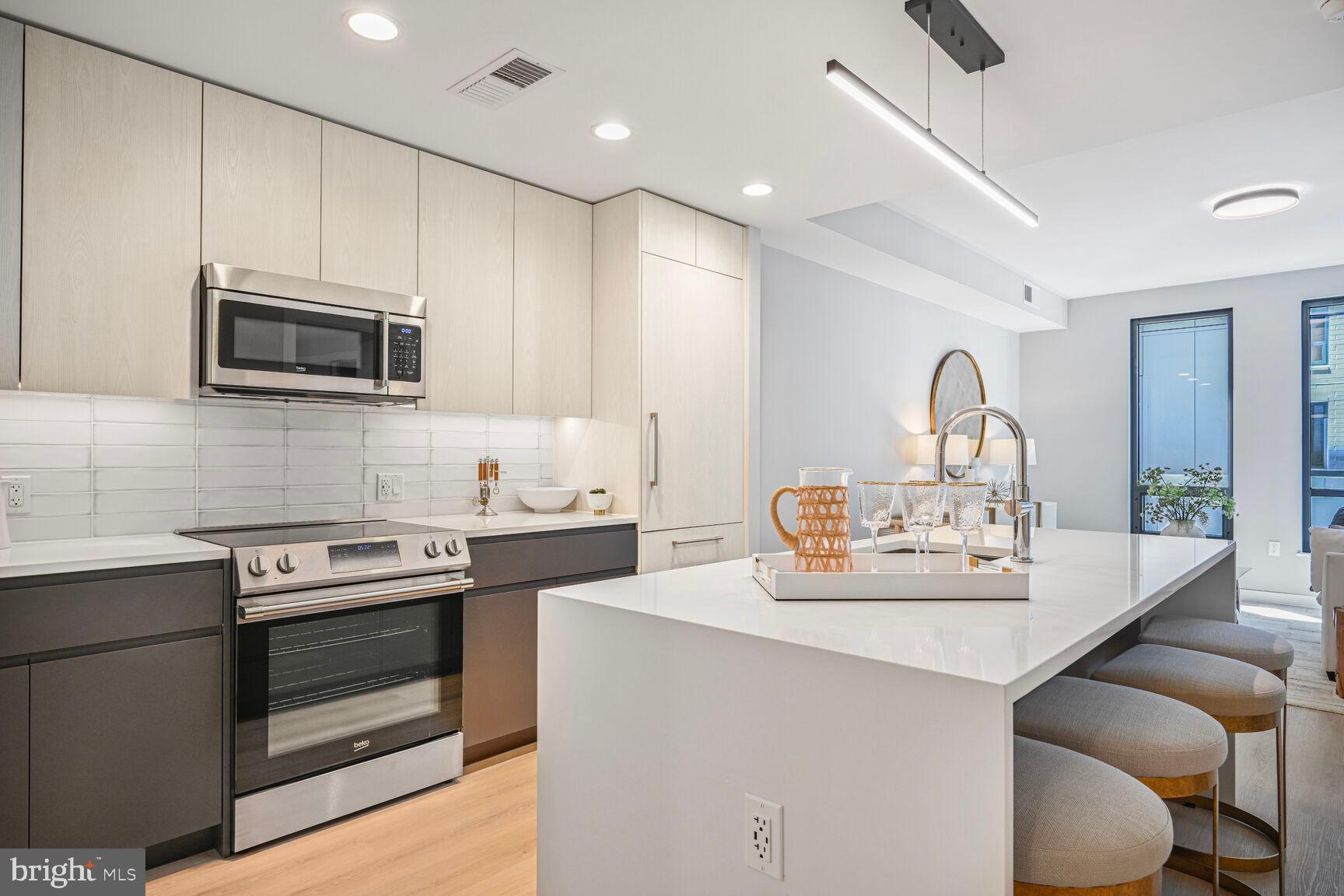 950 3rd Street Northwest, Unit 402 Washington, DC 20001 - Photo 24 of 37 a kitchen with kitchen island granite countertop a stove and a sink