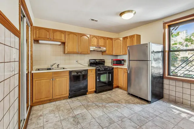 a kitchen with a refrigerator a stove top oven and cabinets