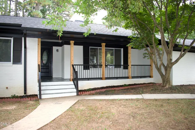 a view of a house with a small yard and a large tree