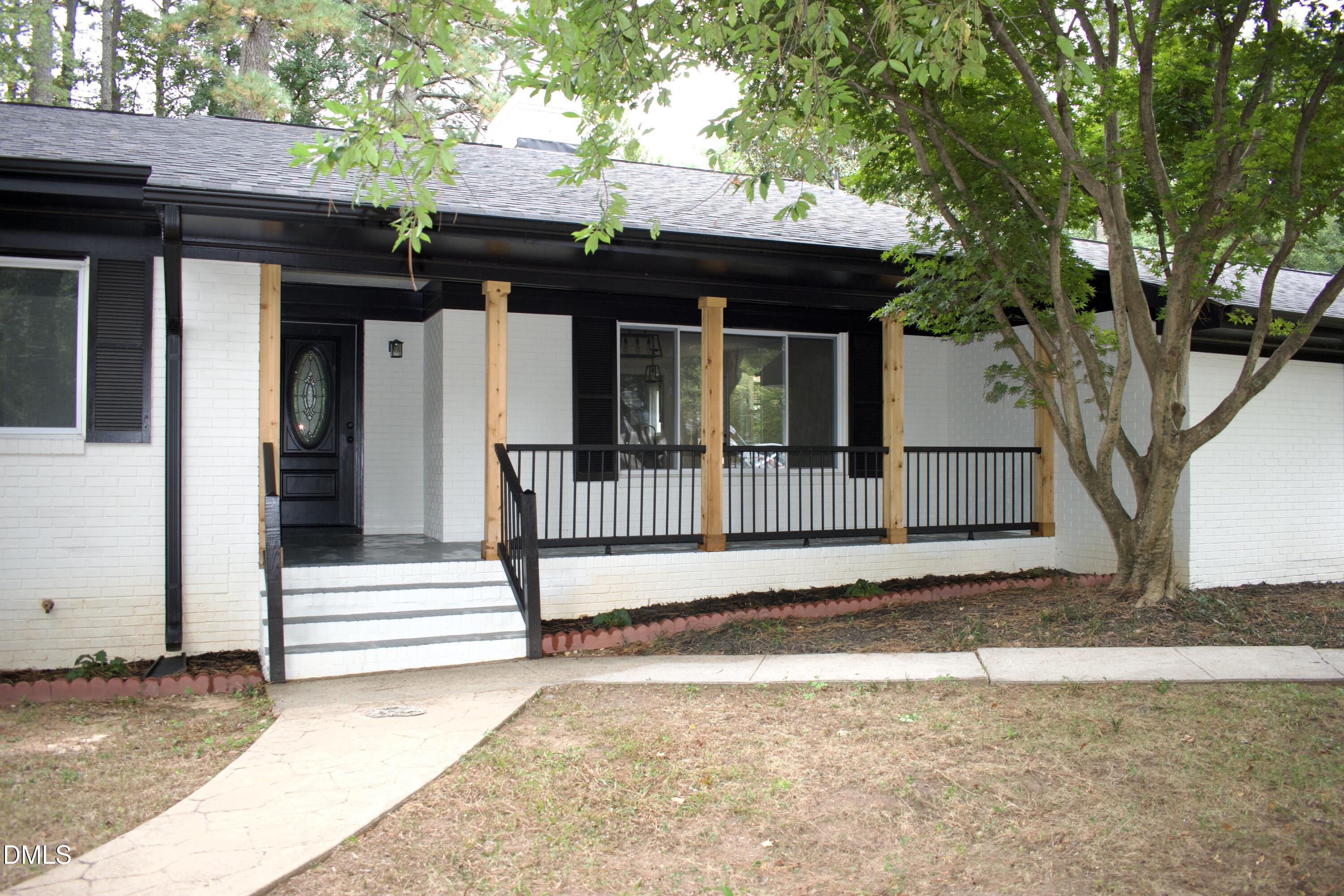 a view of a house with a small yard and a large tree
