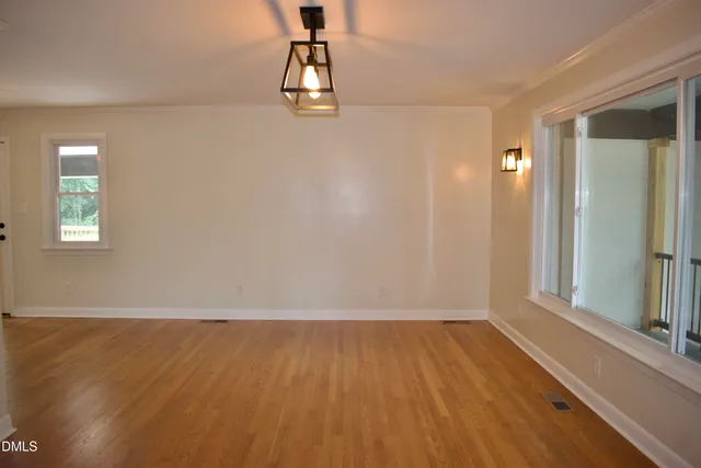 a view of empty room with wooden floor and fan