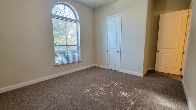 an empty room with windows closet and chandelier fan