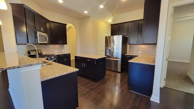a kitchen with stainless steel appliances wooden cabinets a refrigerator and a sink